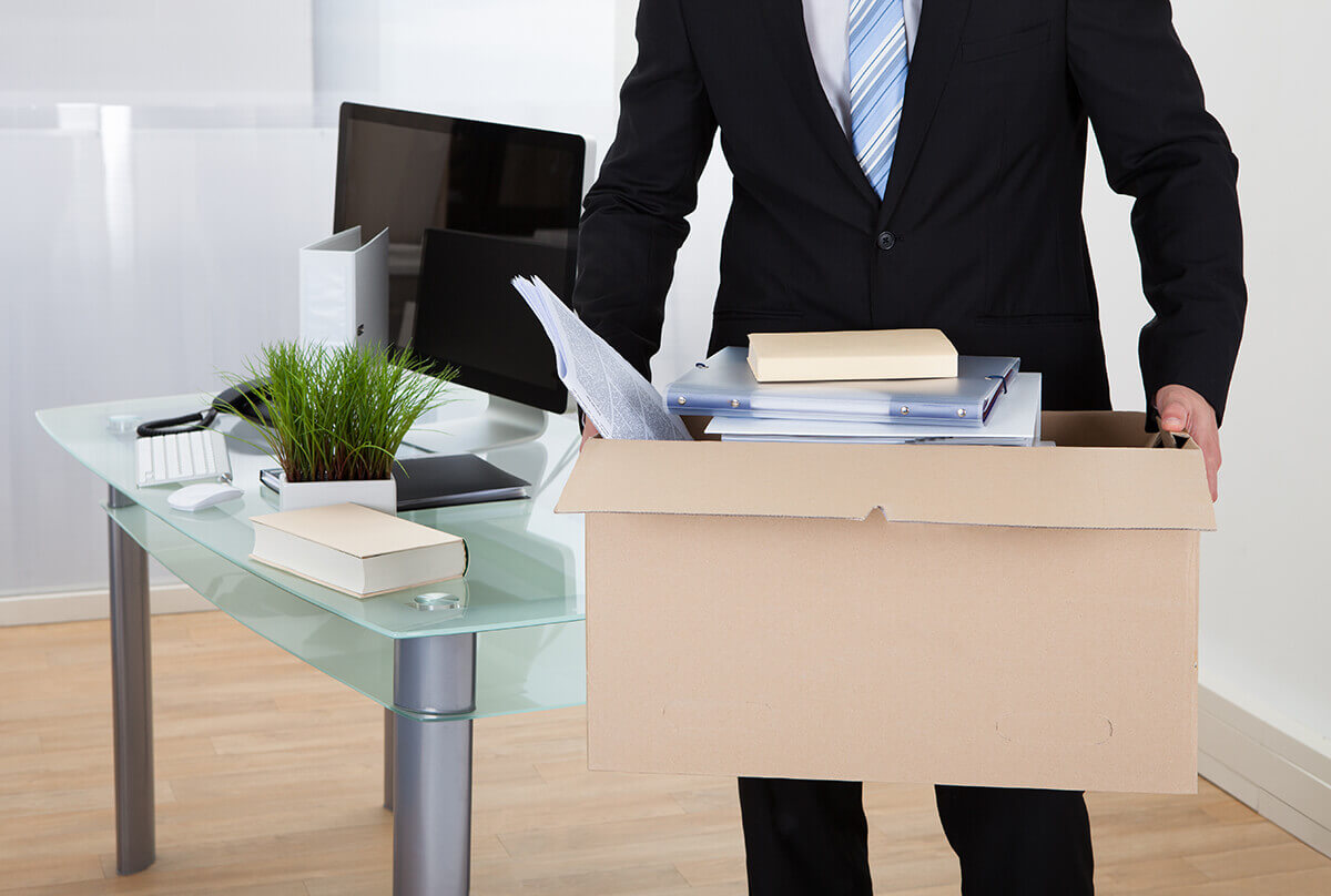 A person holding a box with office supplies. 