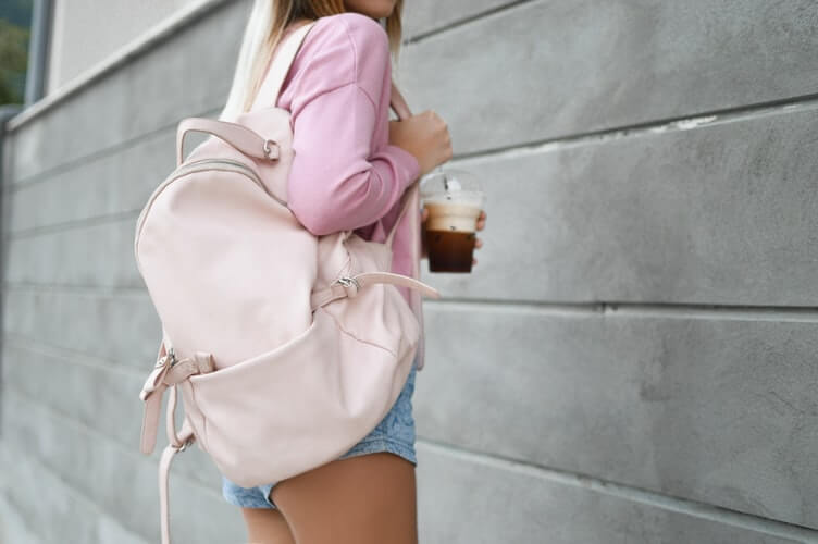 Girl carrying a pink backpack and a coffee