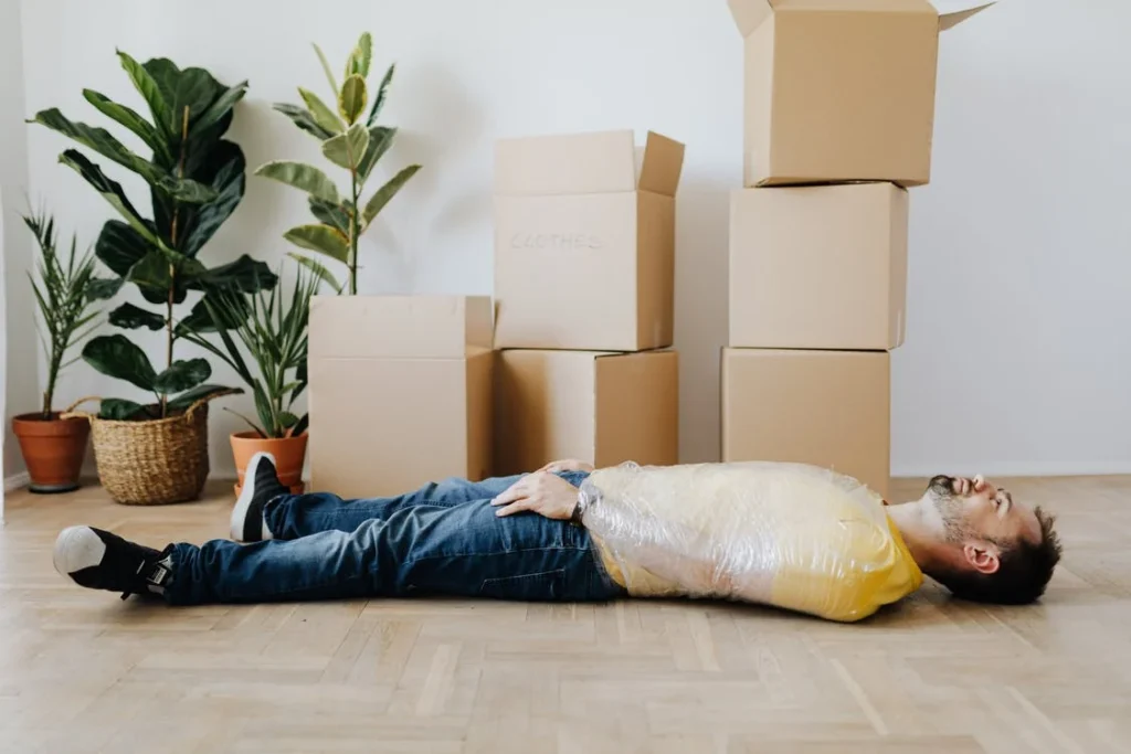 desperate person lying on the floor covered with moving boxes